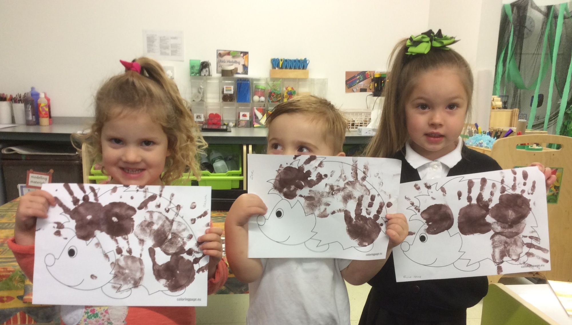 Children smiling in classroom with paintings